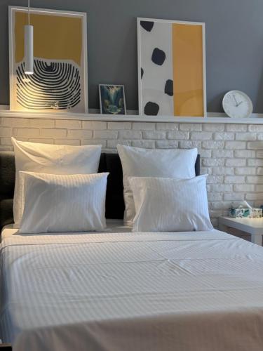 a bedroom with a bed with white sheets and pillows at Divine Studio Fermei 62 in Popeşti-Leordeni