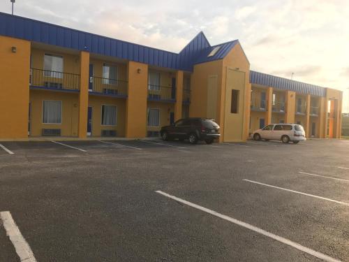 a yellow building with cars parked in a parking lot at Knights Inn Lumberton in Lumberton