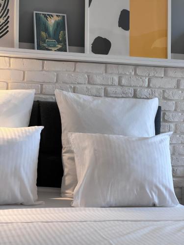 a bed with white pillows and a brick wall at Divine Studio Fermei 62 in Popeşti-Leordeni