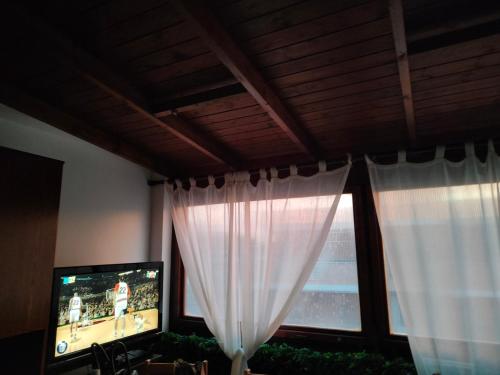 sala de estar con TV y ventana con cortinas en Casa di Luca e Giulia, en Santa Marinella