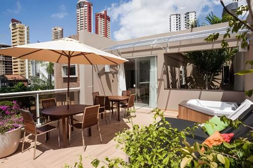 a patio with tables and chairs and an umbrella at Casa moderna com 4 suítes e terraço in Curro Velho