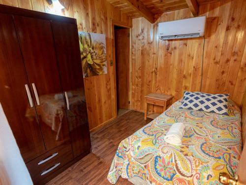 Hotel Catripulli في بوكون: غرفة نوم بها سرير وجدار خشبي
