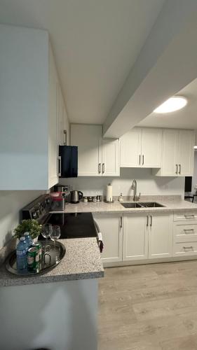 a large kitchen with white cabinets and a sink at Brand new 2 bedroom basement apartment in Ajax