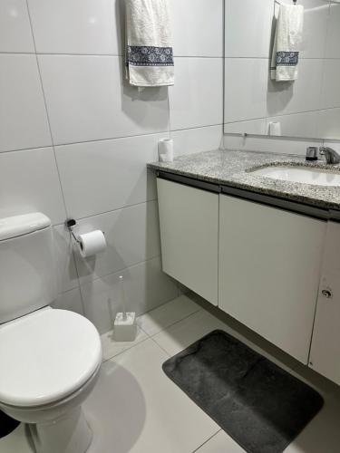 a white bathroom with a toilet and a sink at Flat Privativo Sol Victoria Marina in Salvador