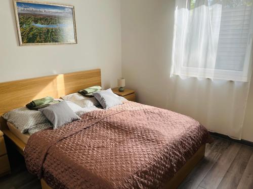 a bedroom with a bed with a red comforter and a window at Central Perk Apartman in Balatonalmádi