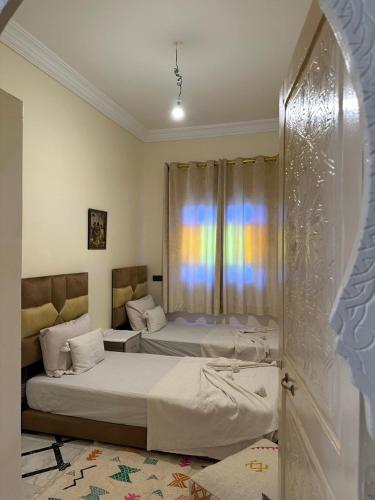 two beds in a room with a rainbow in the window at La Perle d'Aït Faska in Bou Azza