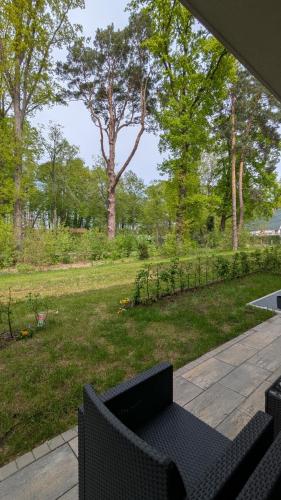 a patio with two chairs and a garden with trees at Neue moderne große Wohnung am See mit Terrasse, Garten, Einbauküche, Badewanne, Dusche, nähe Berlin in Bestensee