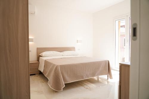 a white bedroom with a bed with a blanket at Kind House in Pozzallo