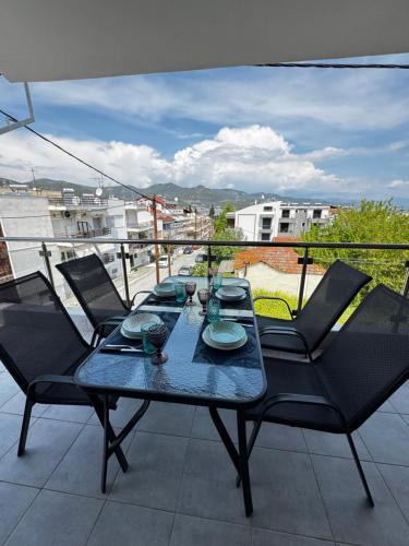 a table with chairs and plates on a balcony at Barounia Suite in Iraklitsa