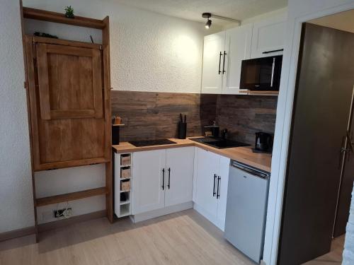 Elle comprend une petite cuisine avec des placards blancs et une porte en bois. dans l'établissement Studio 4P Les orres 1650, aux Orres