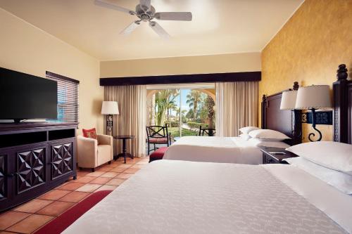 a hotel room with two beds and a flat screen tv at The Club at Hacienda del Mar in Cabo San Lucas