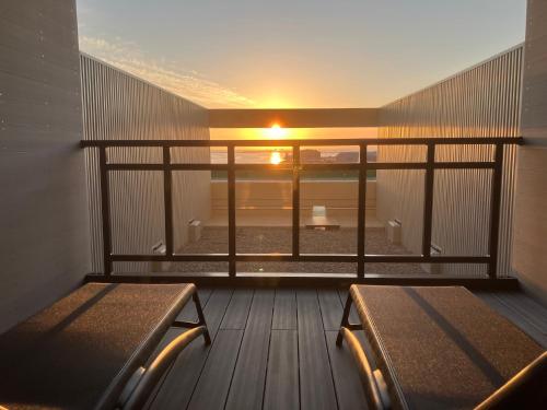 釧路市にあるANAクラウンプラザホテル釧路の夕日が見える部屋にベンチが2つあるバルコニー