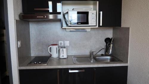 une petite cuisine avec un évier et un micro-ondes dans l'établissement Résidence Median - Studio rénové · Proche des pistes · Balcon MAE-1954, aux Menuires