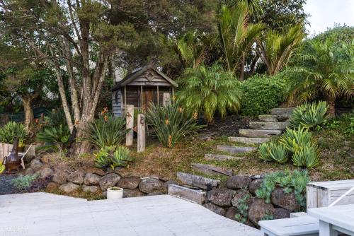 a garden with a small house and some plants at Funky Beach House with sea and country views in Orewa