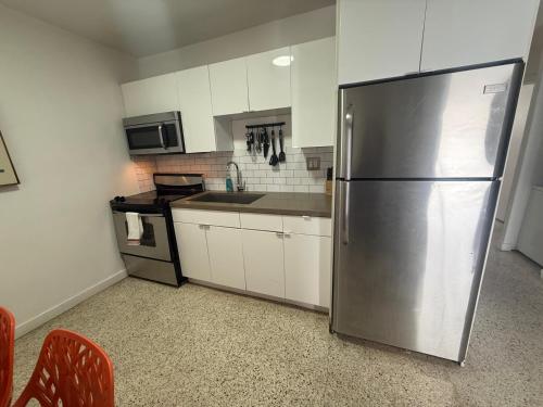 a kitchen with a stainless steel refrigerator and white cabinets at Wynwood Bungalows By Renzzi in Miami