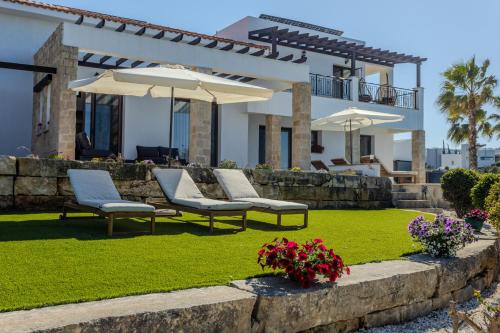 a house with chairs and umbrellas in a yard at Kallisti Beach & Spa Villa - A Luxury Seaside Retreat in Lachi