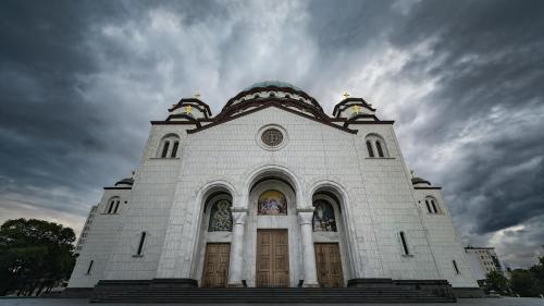 a white church with a cloudy sky in the background at Oaza Apartmani Jakovo AFRODITA in Jakovo