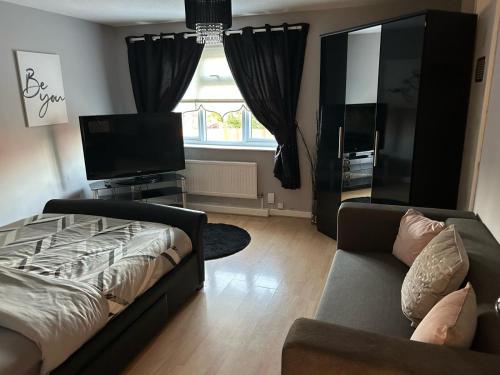 a living room with a bed and a couch and a window at 2 bedroom house close to city centre with gated driveway in Liverpool