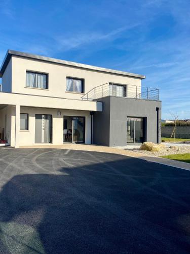 une grande maison blanche avec une allée dans l'établissement villa des rivages, à Cléder