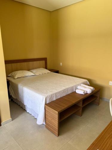 a bedroom with a bed and a wooden table at Hotel do Carmo in Piracuruca