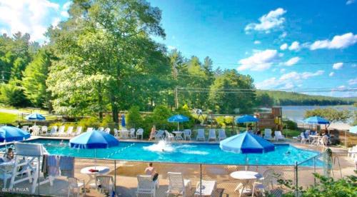 a large swimming pool with blue umbrellas and chairs at Beautiful Lakefront Chalet in the Poconos! in Hawley