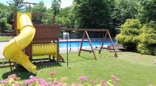 a yellow slide in a park with a pool at Beautiful Lakefront Chalet in the Poconos! in Hawley