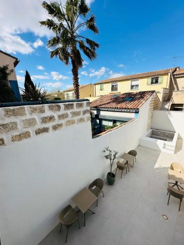 a patio with chairs and a white wall and a palm tree at 27 côté remparts in Aigues-Mortes