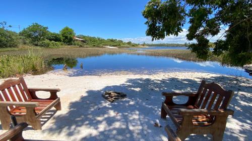 two chairs sitting on the sand near a body of water at Casa completa Porto Sauipe in Porto de Sauipe