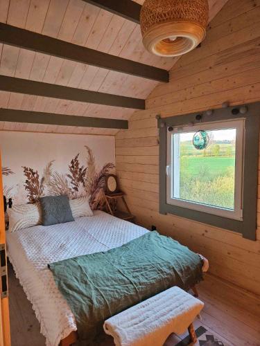 a bedroom with a bed in a room with a window at Dzika Warmia- domek bez sąsiadów na Warmii z balią i kominkiem in Glebisko