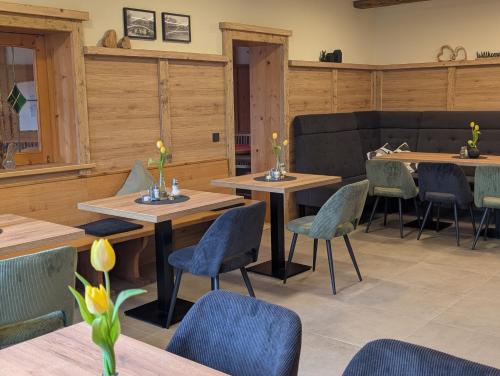 a restaurant with wooden tables and blue chairs at Gästehaus Arracher Hof in Arrach