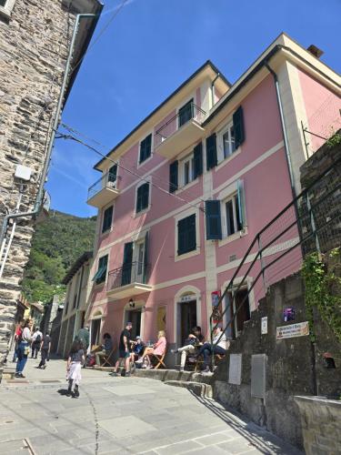 a pink building with people sitting outside of it at Pensione Sorriso in Vernazza