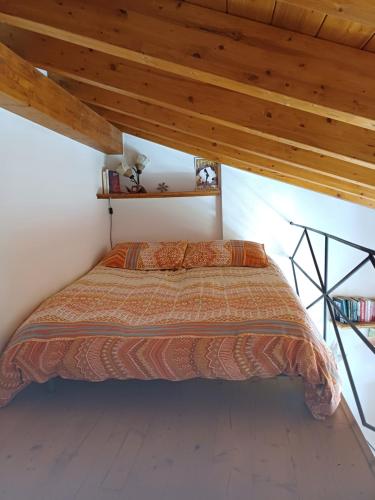 a bed in a room with a wooden ceiling at CASA VISTA LAGO E GIARDINO in Porlezza
