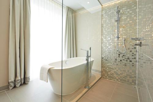 a bathroom with a tub and a glass shower at Steigenberger Hotel Am Kanzleramt in Berlin