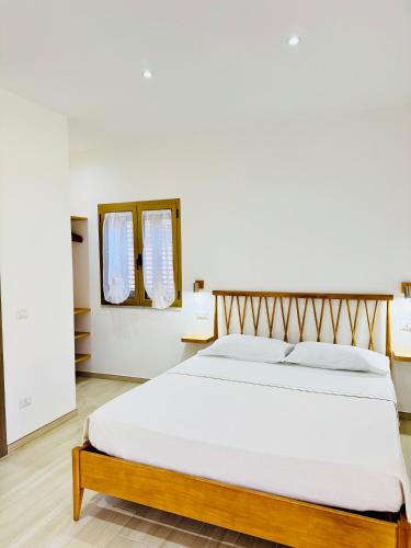 a bedroom with a large white bed and a mirror at CASA SACURI in Rudalza