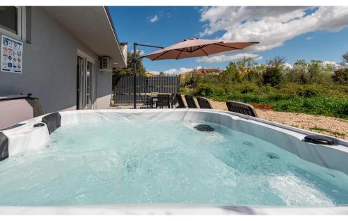 a hot tub with an umbrella on a patio at Awesome Home In Povljana With Wifi in Povljana