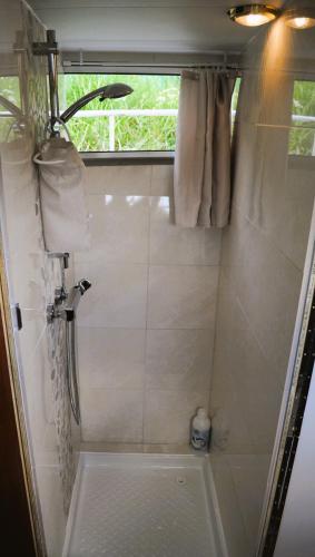 La petite salle de bains est pourvue d'une douche et d'une fenêtre. dans l'établissement C'la Vie - Proche Fontainebleau - Bateau, à Nemours