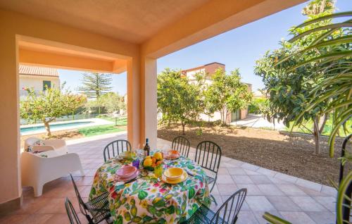 a table and chairs on a patio with a view of a yard at Lovely Home In Piane Vecchie,Lascari in Lascari