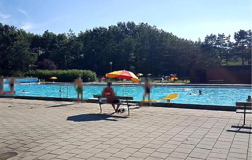 a person sitting under an umbrella next to a swimming pool at Cozy Home In Dalby With Wifi in Dalby
