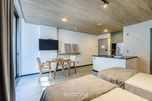 a room with two beds and a table and a kitchen at NWTs - Estúdios em Prédio com Vista Mar in Maceió