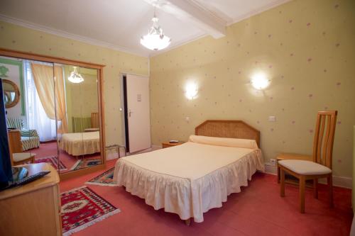 a bedroom with a large bed and a mirror at Hôtel Saint Vincent in Bagnères-de-Bigorre