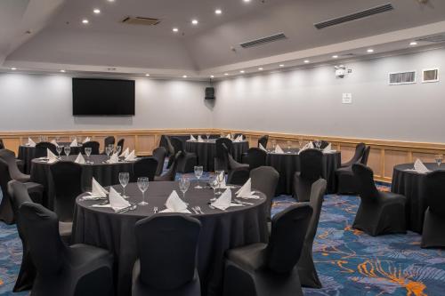 a conference room with tables and chairs and a screen at Crowne Plaza San Jose La Sabana by IHG in San José