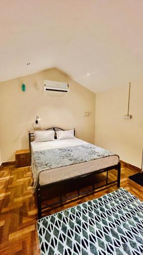 a bedroom with a bed and a rug on the floor at Garden Aroma Palolem, Beachside Hostel & Cafe Bar in Palolem