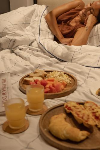 a woman laying in bed with two plates of food at One-Off Dashashwamedh in Varanasi