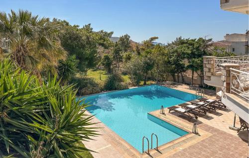 a large swimming pool with lounge chairs and trees at Gorgeous Home In Lagonisi With Wifi in Lagonissi