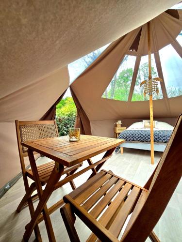une table et des chaises en bois dans une tente dans l'établissement Les nuits de Cassiopee, à Sorde-lʼAbbaye