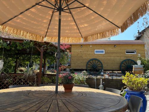 a wooden table with an umbrella on a patio at La Petalerie in Épernay