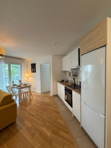 une cuisine avec des placards blancs, une table et une table dans l'établissement Luxury and Cozy Apartement In la Defense-Paris, à Courbevoie