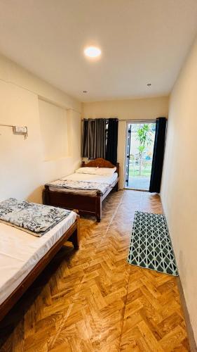 a room with two beds and a wooden floor at Garden Aroma Palolem, Beachside Hostel & Cafe Bar in Palolem