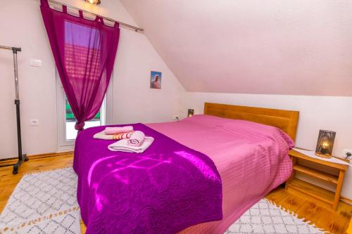 a bedroom with a purple bed with a purple blanket at House Moj mir in Primošten