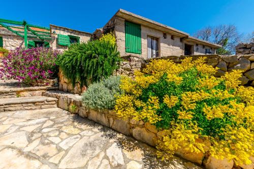 a stone retaining wall with flowers in front of a house at House Moj mir in Primošten